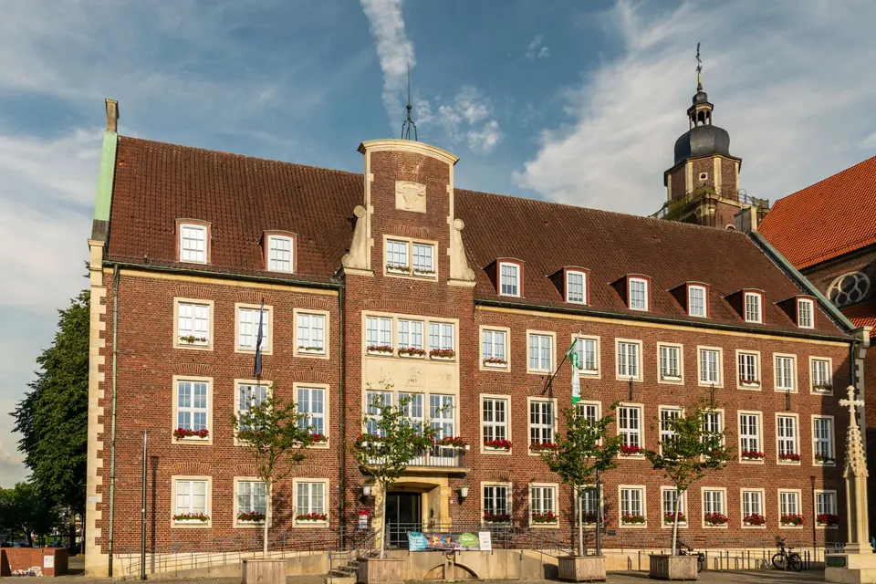 Ein historisches Rathausgebäude mit klassischer Architektur, das in lebhaftem Sonnenlicht im Freien badet.